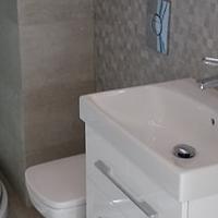 Łazienka z meblami w kolorze białym oraz płytkami w kolorach beżu pomieszanego z szarym